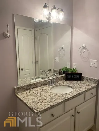 a bathroom with a granite countertop sink and a mirror
