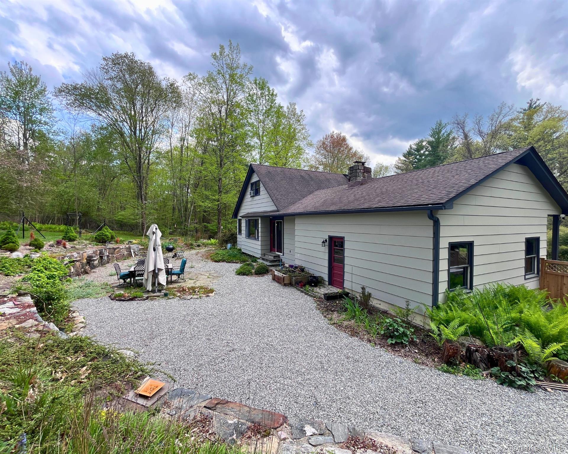 64 Belden Road Carmel, NY 10512 - Photo 16 of 23 Patio with table, umbrella, and fire pit surrounded by lush landscaping