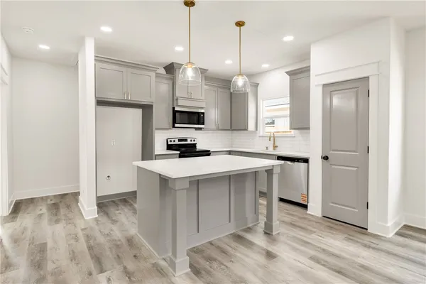 a kitchen with kitchen island a sink stainless steel appliances and white cabinets