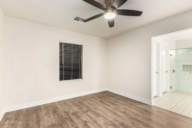 an empty room with wooden floor fan and windows