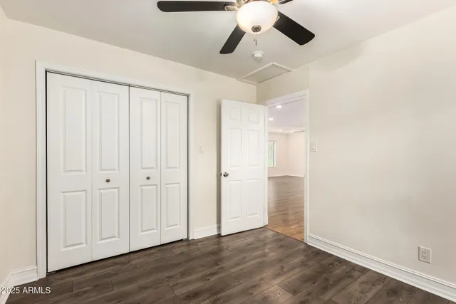 an empty room with wooden floor cabinet and windows