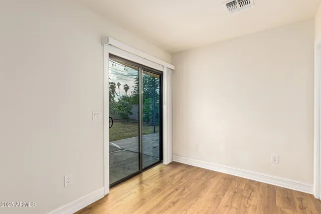 a view of an empty room with wooden floor and a window