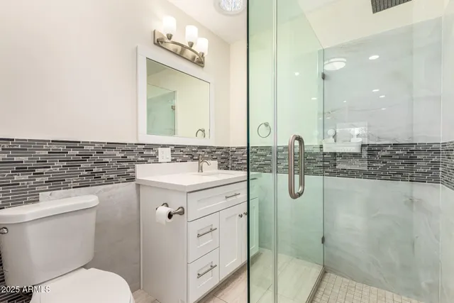 a bathroom with a granite countertop sink mirror vanity and toilet