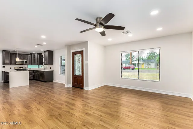 a view of an empty room with kitchen view and a window