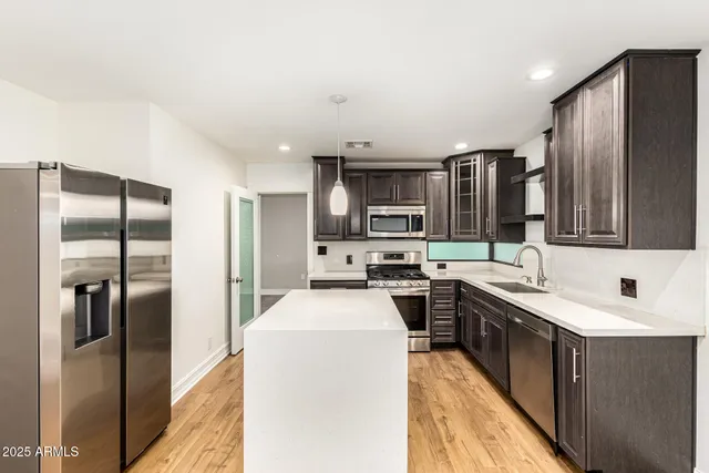 a kitchen with stainless steel appliances a sink stove refrigerator and cabinets