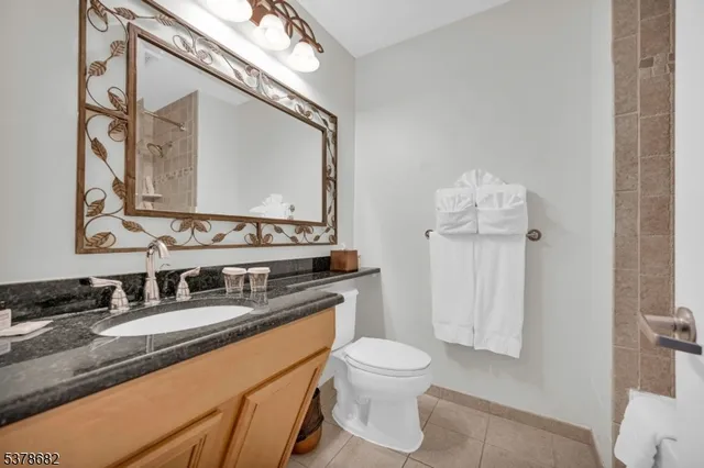 a bathroom with a granite countertop sink mirror vanity and toilet