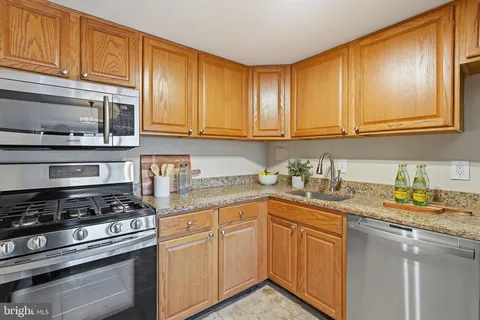 a kitchen with granite countertop stainless steel appliances a stove sink and cabinets