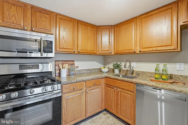 a kitchen with granite countertop stainless steel appliances a stove sink and cabinets