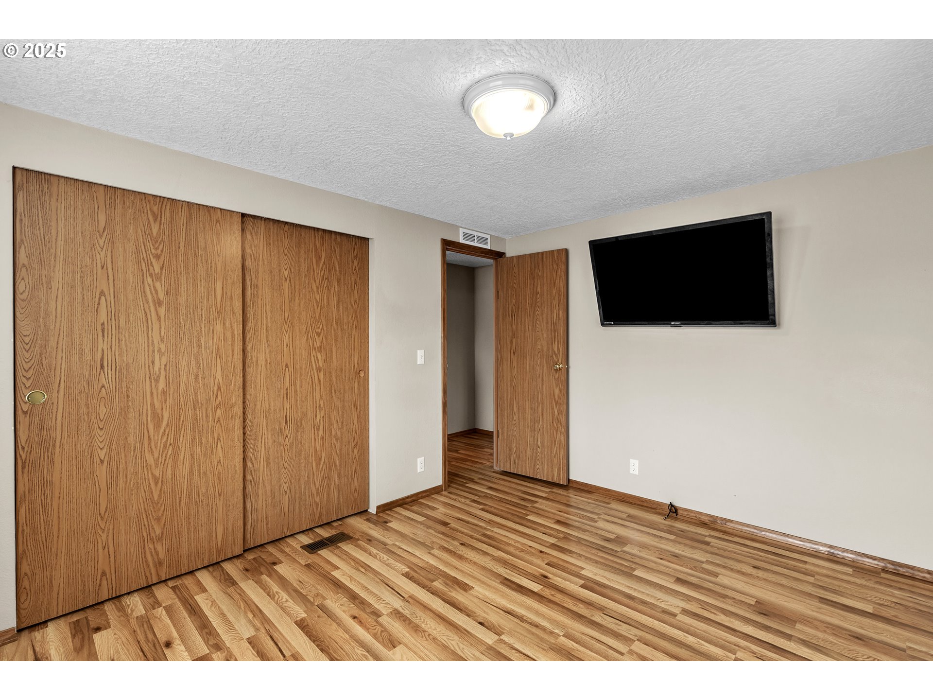 5701 Northeast St Johns Road, Unit 4 Vancouver, WA 98661 - Photo 16 of 28 a view of an empty room with wooden floor and a flat screen tv