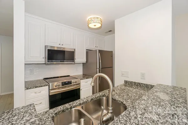 a kitchen with stainless steel appliances granite countertop a stove refrigerator and microwave