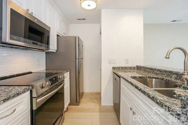 a kitchen with granite countertop a sink and stainless steel appliances