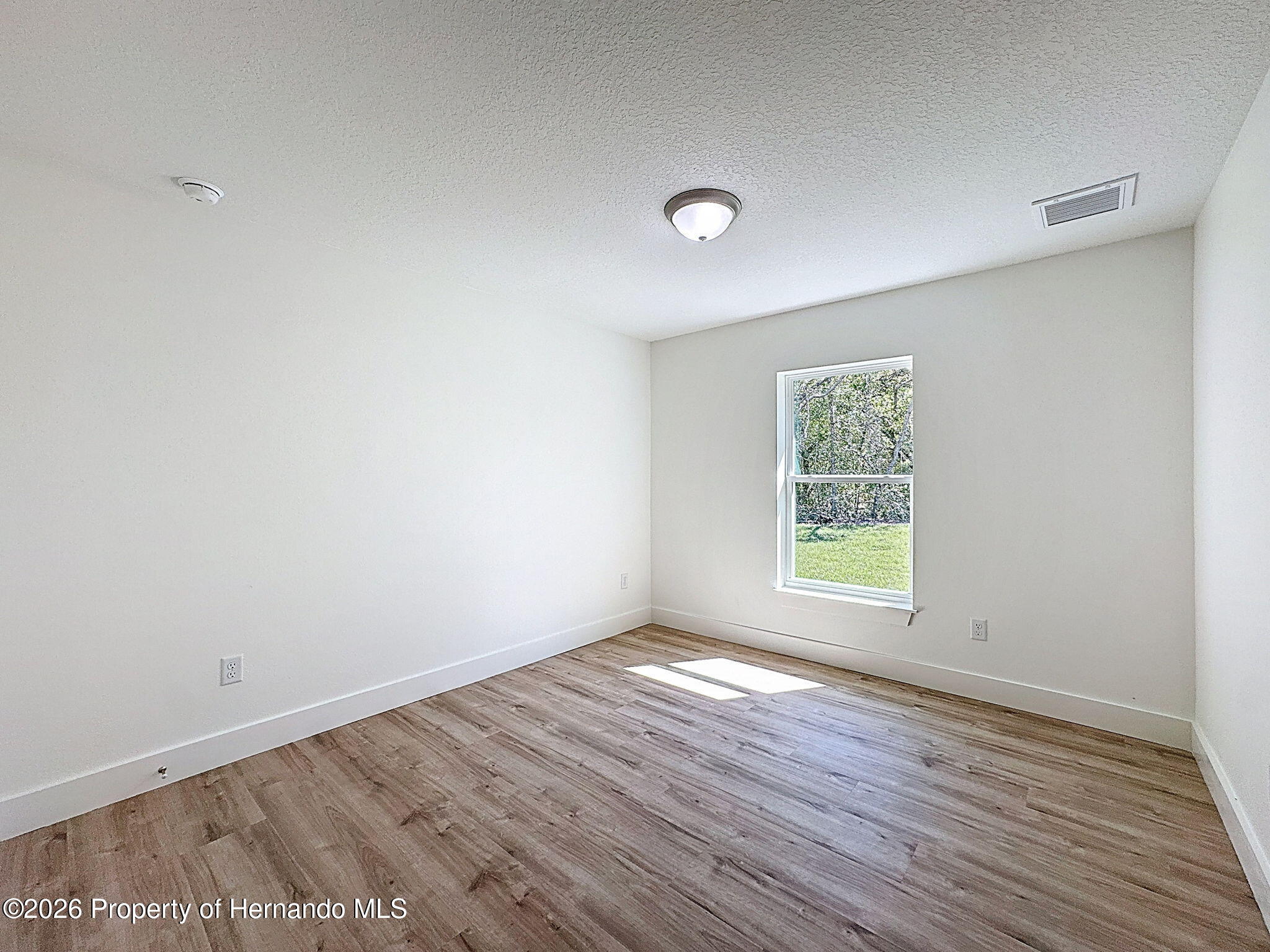 8988 Waterbird Way Weeki Wachee, FL 34613 - Photo 38 of 42 an empty room with wooden floor and window