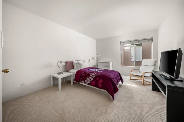 a bedroom with a bed and flat tv screen on the dresser
