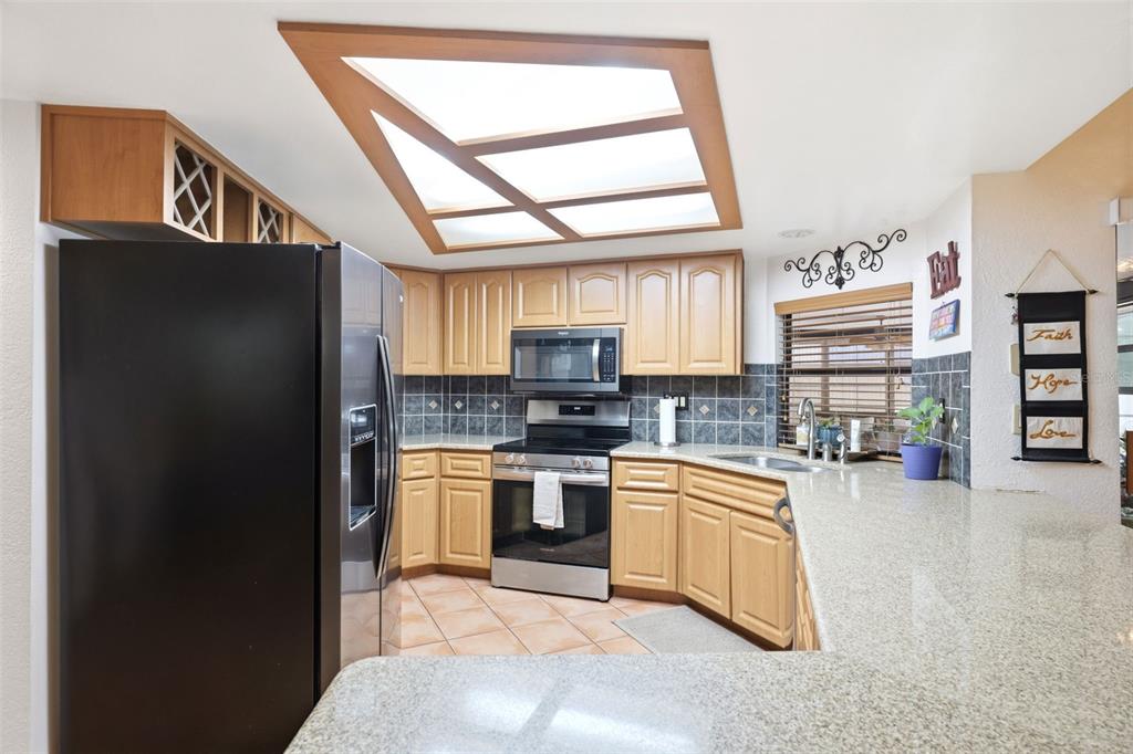 5227 Suwannee Road Weeki Wachee, FL 34607 - Photo 17 of 62 a kitchen with stainless steel appliances granite countertop a refrigerator and a stove top oven