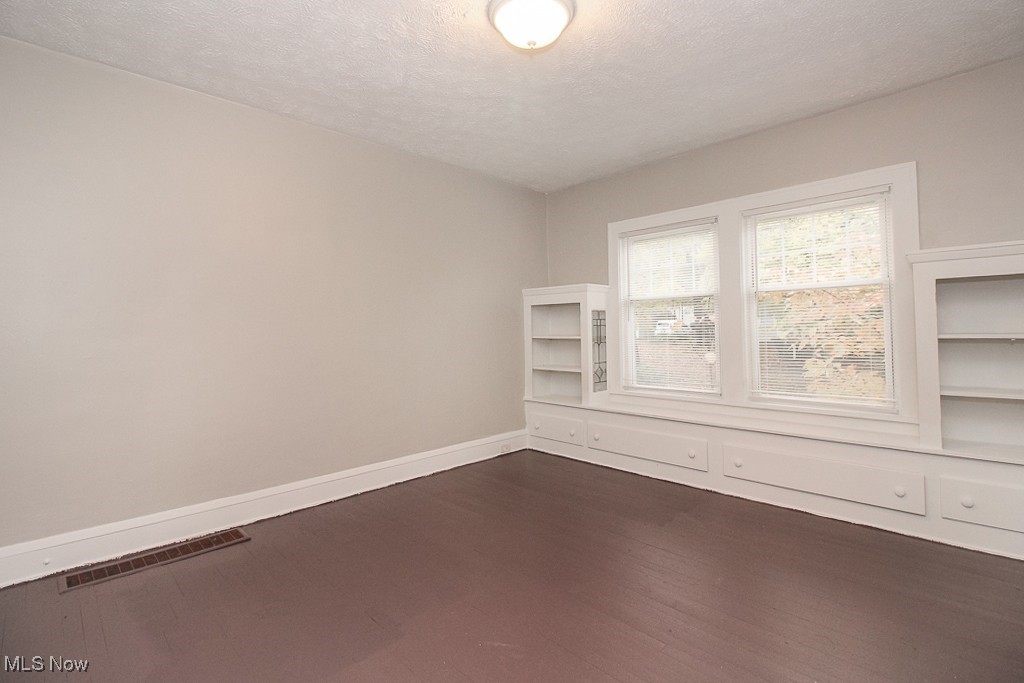 3085 Somerton Road Cleveland, OH 44118 - Photo 9 of 16 Unfurnished room featuring visible vents, a textured ceiling, baseboards, and dark wood-style flooring