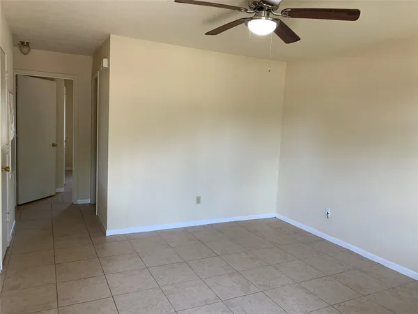 an empty room with a ceiling fan and carpet