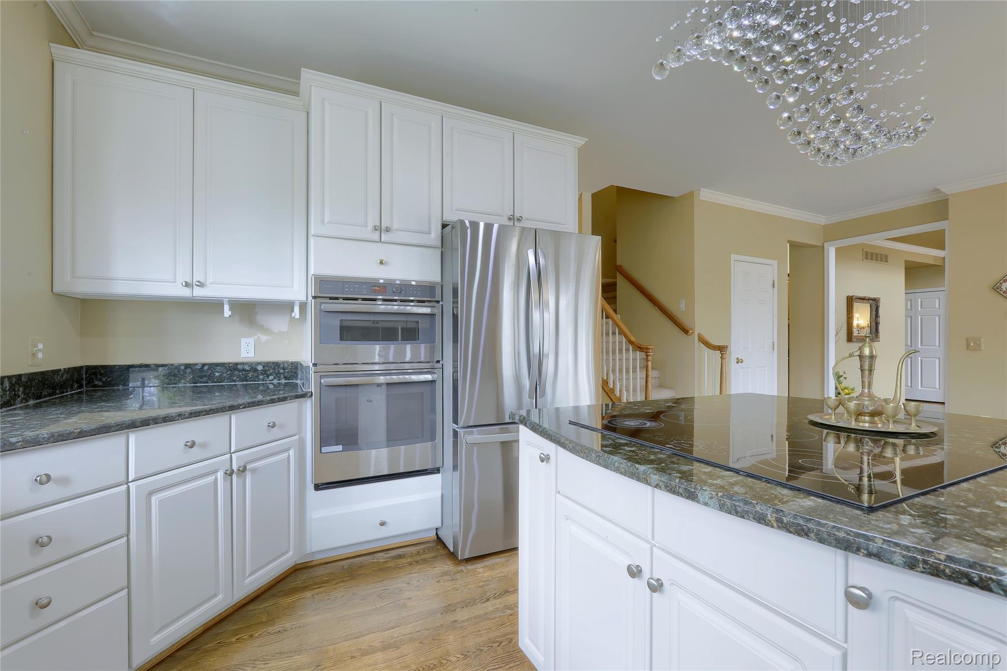 2007 Mapleridge Road Rochester, MI 48309 - Photo 17 of 45 Kitchen featuring white cabinetry, ornamental molding, stainless steel appliances, light wood finished floors, and dark stone counters
