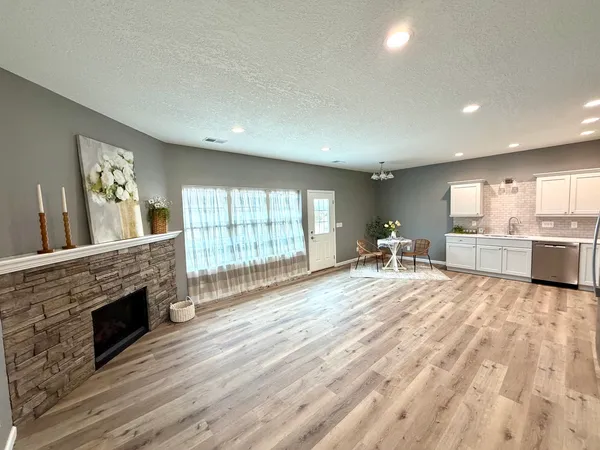a large white kitchen with wooden floors and a fireplace