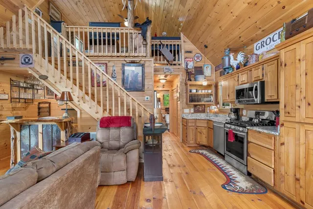 a kitchen with stainless steel appliances granite countertop a living room kitchen island a stove and a wooden floors