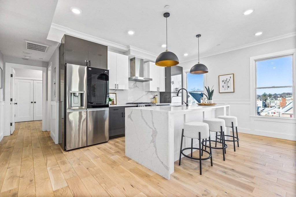 a kitchen with stainless steel appliances kitchen island a table chairs in it and wooden floors