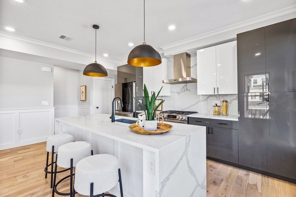 14 Hillside Park, Unit 6 Somerville, MA 02143 - Photo 6 of 32 a kitchen with a refrigerator a stove and white cabinets with wooden floor