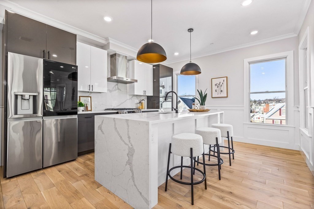 14 Hillside Park, Unit 6 Somerville, MA 02143 - Photo 8 of 32 a kitchen with stainless steel appliances granite countertop a refrigerator a sink dishwasher a dining table and chairs with wooden floor