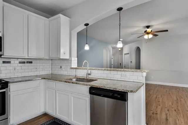 a kitchen with a sink dishwasher and white cabinets