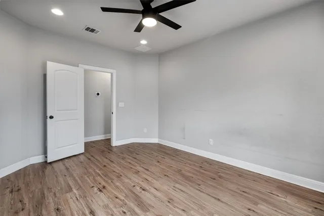 an empty room with wooden floor a ceiling fan and staircase