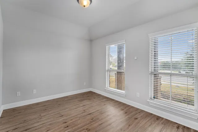 an empty room with wooden floor and windows