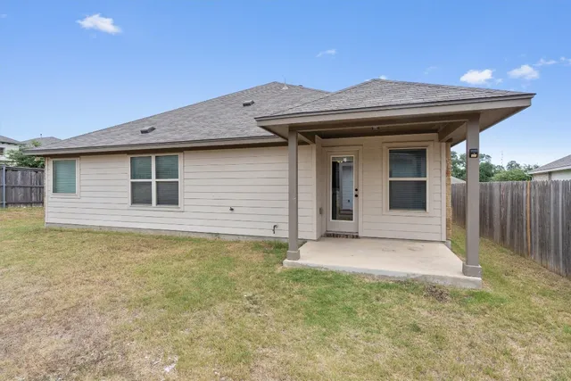 a view of an house with backyard space and wooden fence