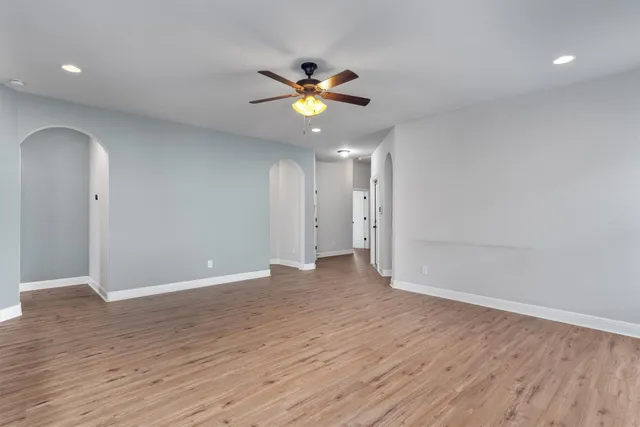 a view of an empty room with a ceiling fan and wooden floor