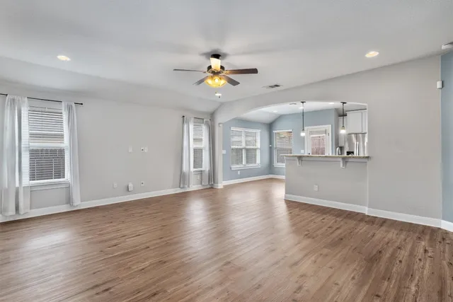 a view of an empty room with kitchen and window