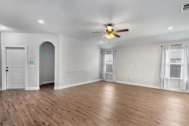 a view of an empty room with a window and wooden floor