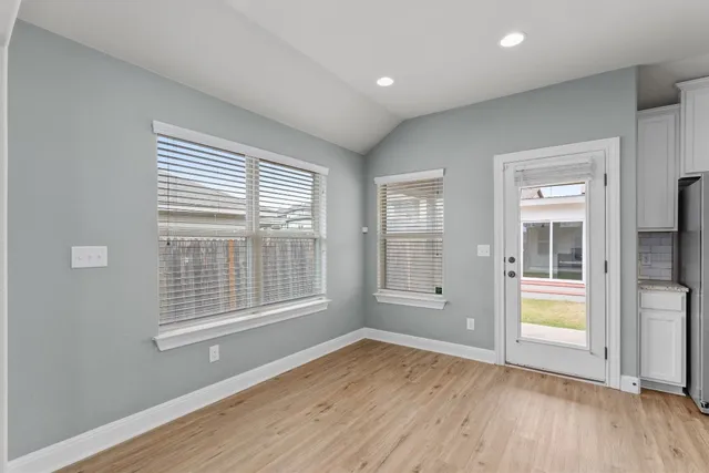 an empty room with wooden floor and windows