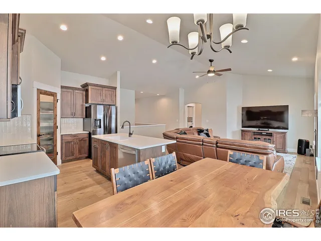 a kitchen with stainless steel appliances kitchen island granite countertop a refrigerator and a view of living room