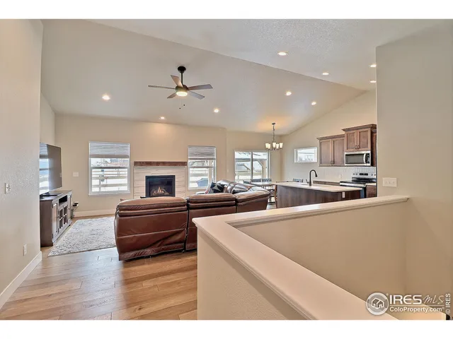 a kitchen with stainless steel appliances kitchen island granite countertop a refrigerator oven a sink dishwasher and a fireplace with wooden floor