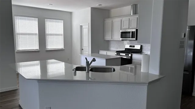 a kitchen with granite countertop a sink a counter top space cabinets and stainless steel appliances