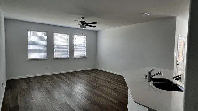 a view of an empty room with a window and wooden floor