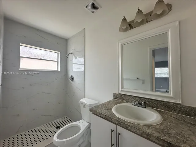 a bathroom with a granite countertop sink a toilet and a mirror