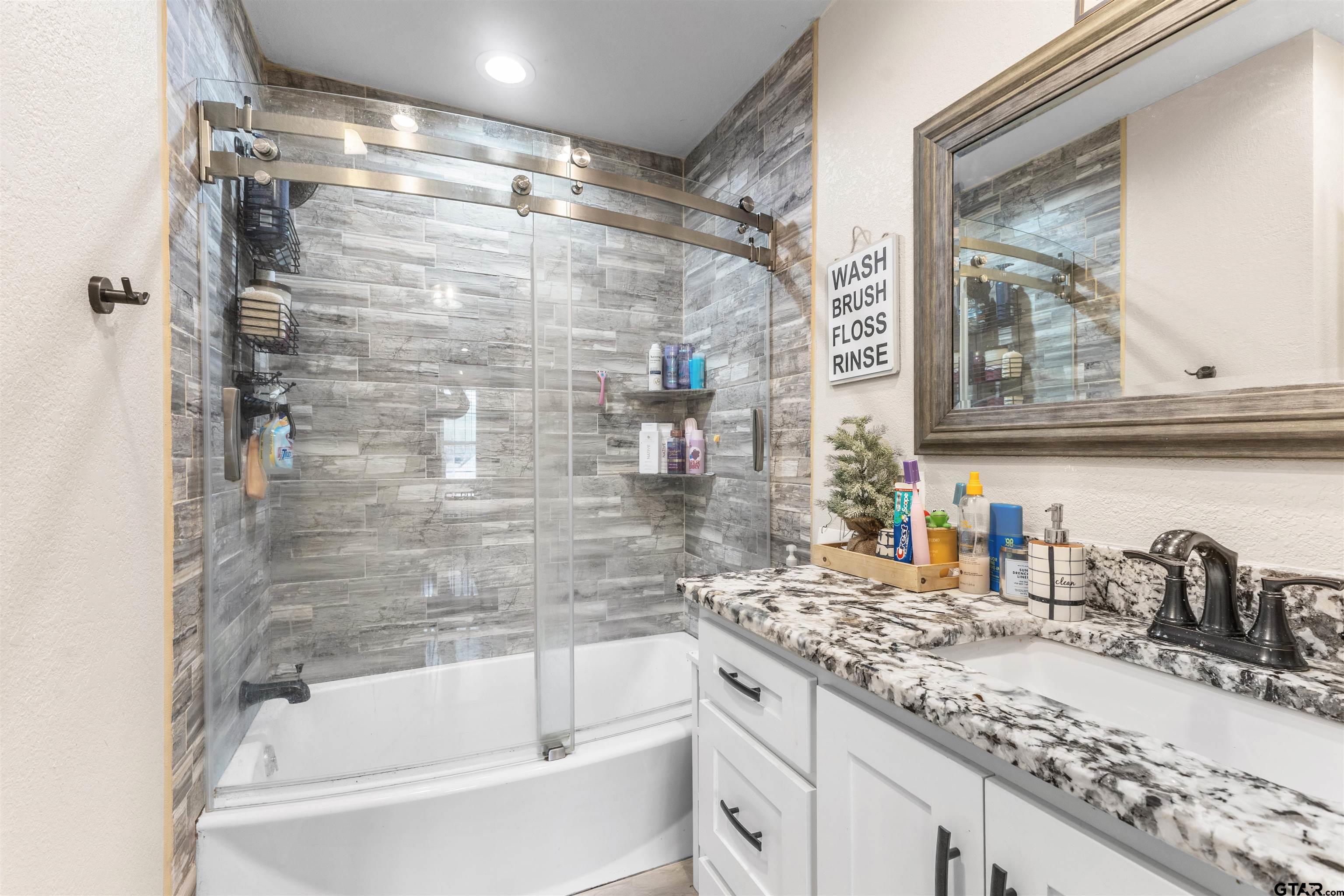 106 Pecan Ridge Mount Vernon, TX 75457 - Photo 23 of 31 a bathroom with a granite countertop sink mirror bathtub and shower