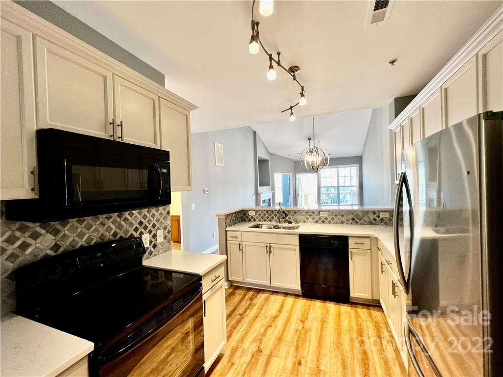 18742 Nautical Drive, Unit 305 Cornelius, NC 28031 - Photo 8 of 30 a kitchen with stainless steel appliances kitchen island granite countertop a stove a sink and a refrigerator
