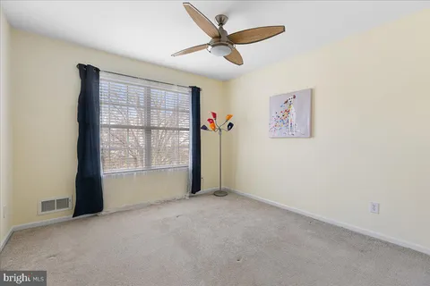 an empty room with a ceiling fan and window