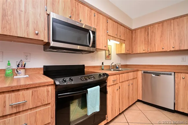 a kitchen with stainless steel appliances a dining table chairs refrigerator and sink