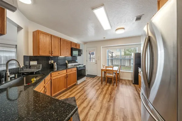 a kitchen with stainless steel appliances granite countertop sink stove refrigerator and cabinets