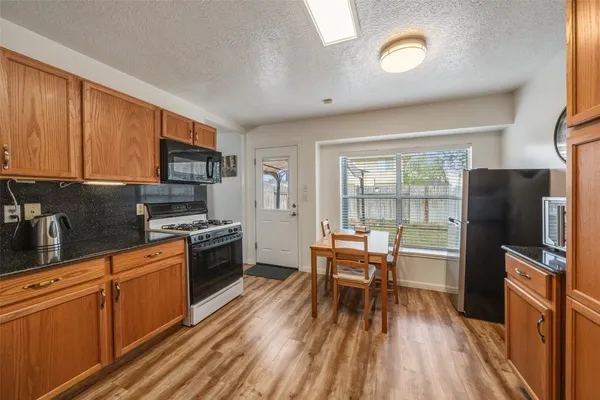 a kitchen with stainless steel appliances a stove top oven a sink dishwasher and a refrigerator with wooden floor