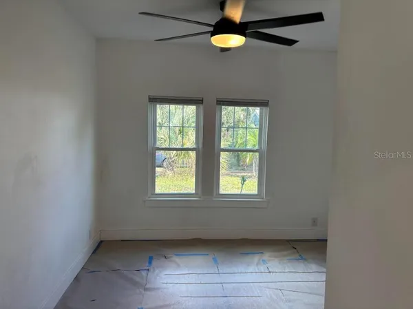 an empty room with windows and fan