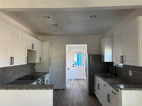 a kitchen with granite countertop a sink a stove and refrigerator