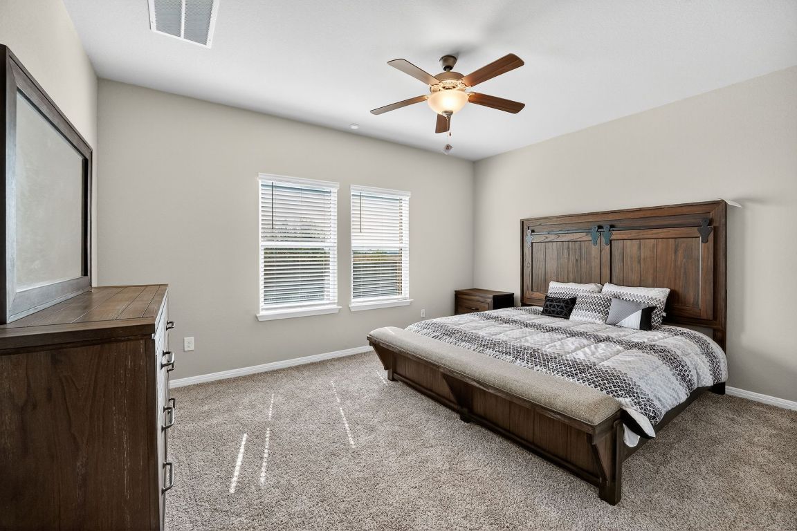 17801 Prairie Land Way Manor, TX 78653 - Photo 15 of 31 a spacious bedroom with a bed and a chandelier