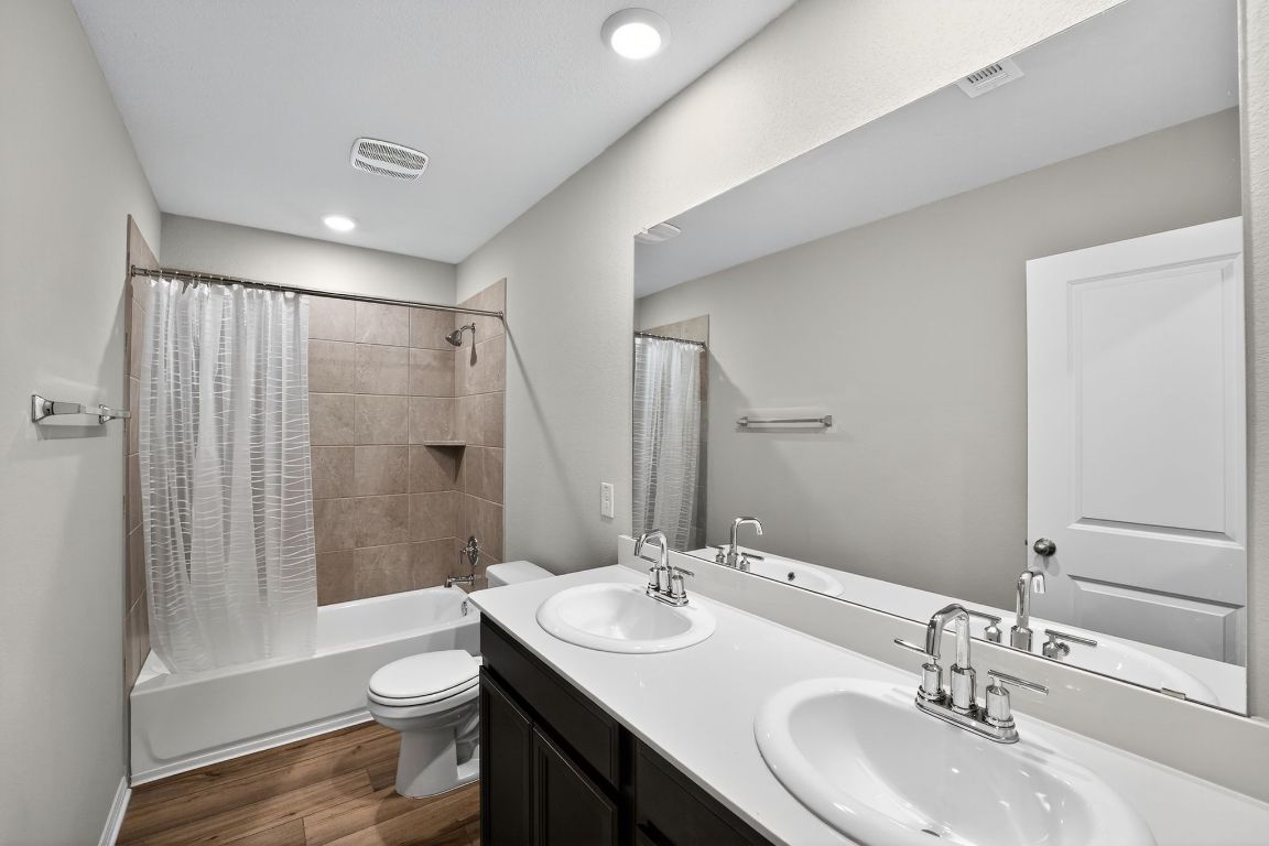 17801 Prairie Land Way Manor, TX 78653 - Photo 24 of 31 a bathroom with a sink a toilet a mirror a vanity and shower