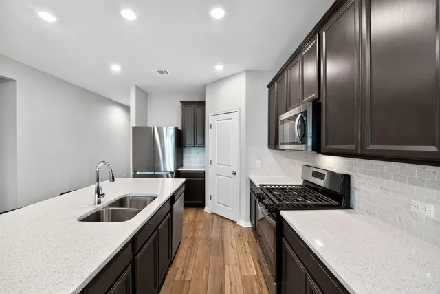 a kitchen with stainless steel appliances granite countertop a sink a stove and a refrigerator